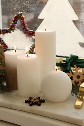 Beautiful burning candles with Christmas decor on windowsill indoors