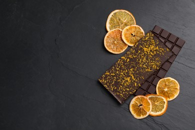 Photo of Chocolate bars with freeze dried orange on slate table, flat lay. Space for text