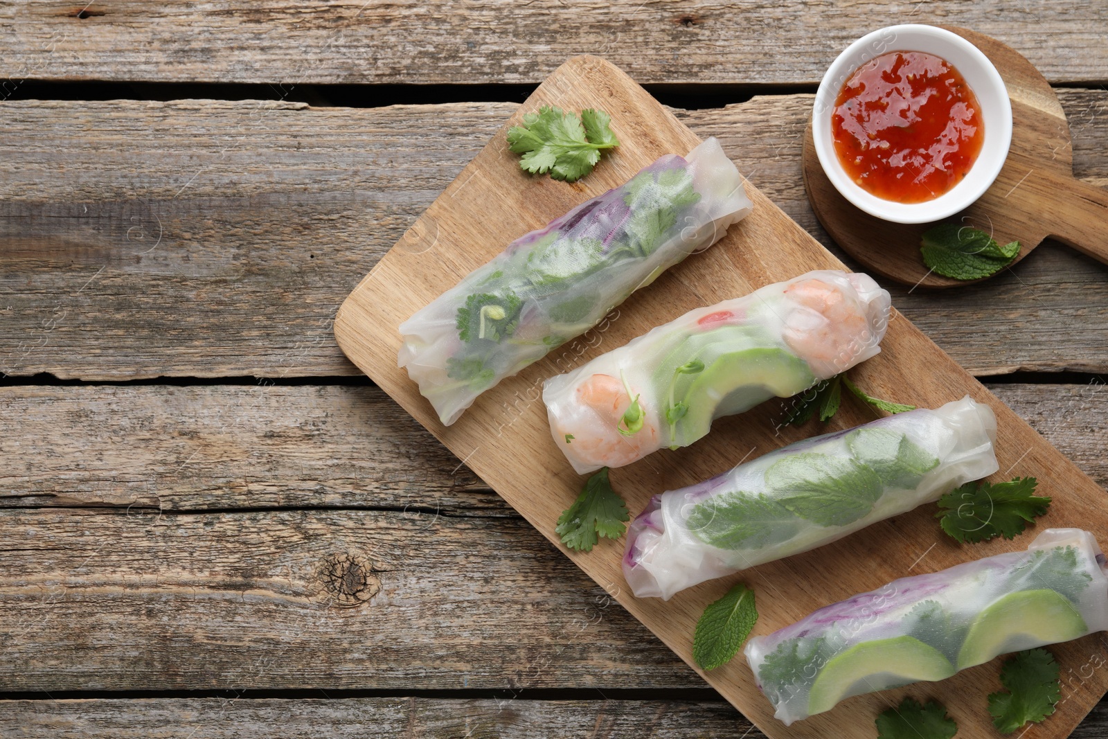 Photo of Delicious spring rolls, sauce and chopsticks on wooden table, top view. Space for text