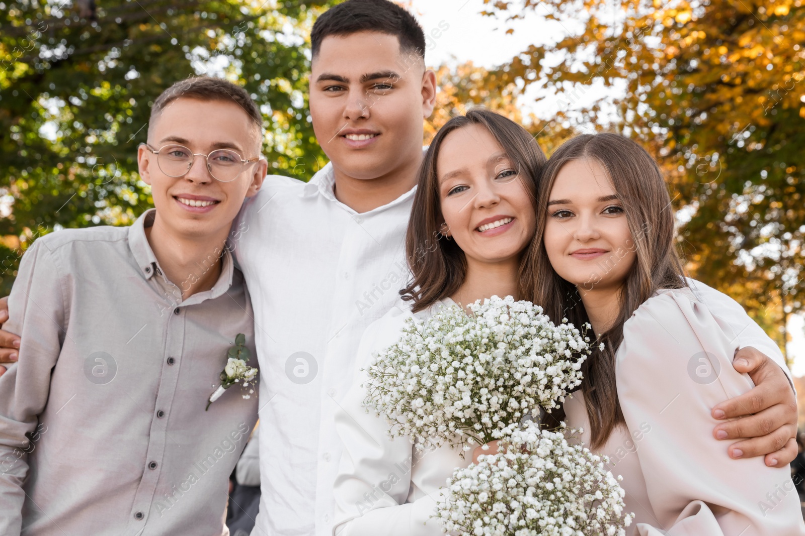 Photo of Happy newlywed couple and their friends outdoors. Wedding day