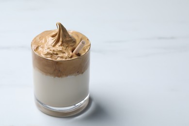 Glass of delicious dalgona coffee on white marble table, closeup. Space for text