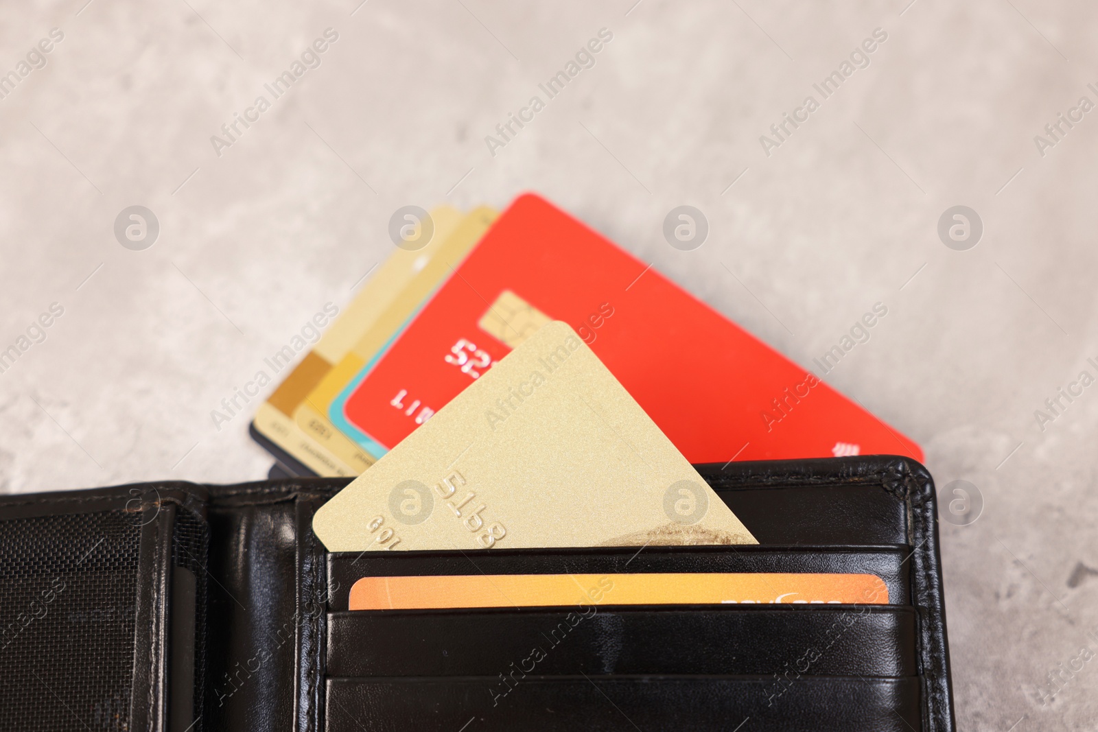 Photo of Many different credit cards and leather wallet on grey table, closeup