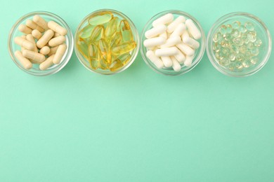 Photo of Different vitamin capsules in glass bowls on turquoise background, flat lay. Space for text
