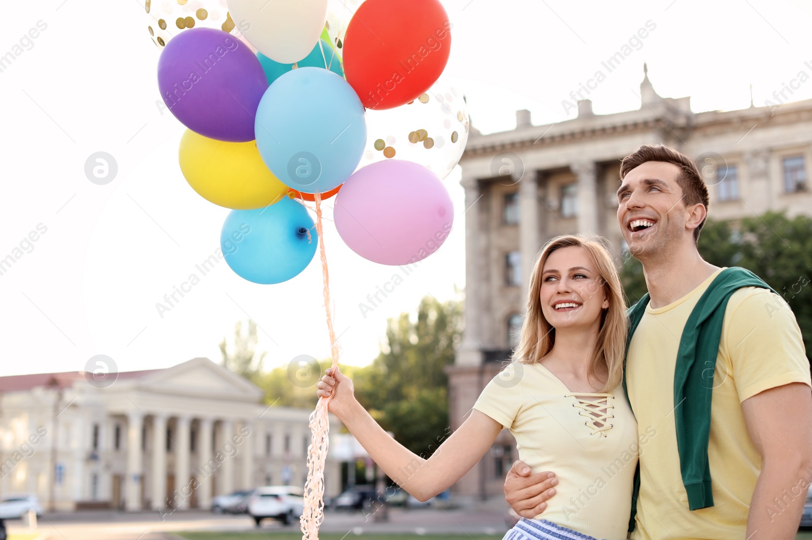 Photo of Young couple with colorful balloons outdoors on sunny day