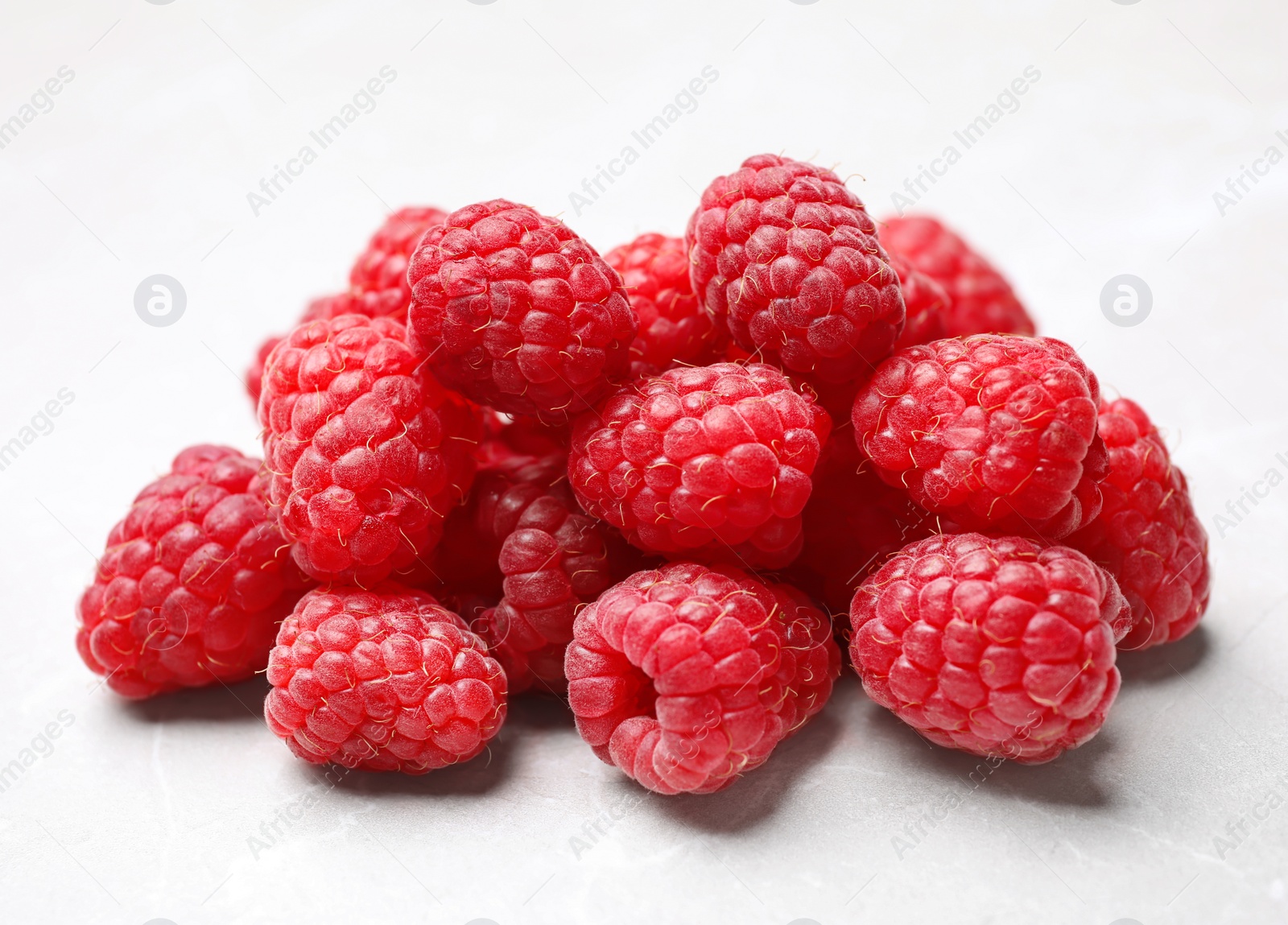 Photo of Delicious fresh ripe raspberries on white table, closeup