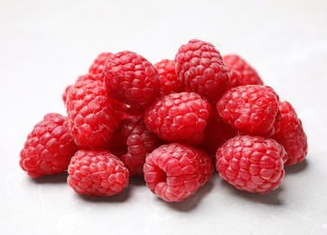 Photo of Delicious fresh ripe raspberries on white table, closeup