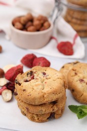 Photo of Cookies with freeze dried fruits, nuts and mint on white table, closeup