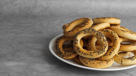 Photo of Plate with delicious ring shaped Sushki (dry bagels) on light grey table, closeup. Space for text
