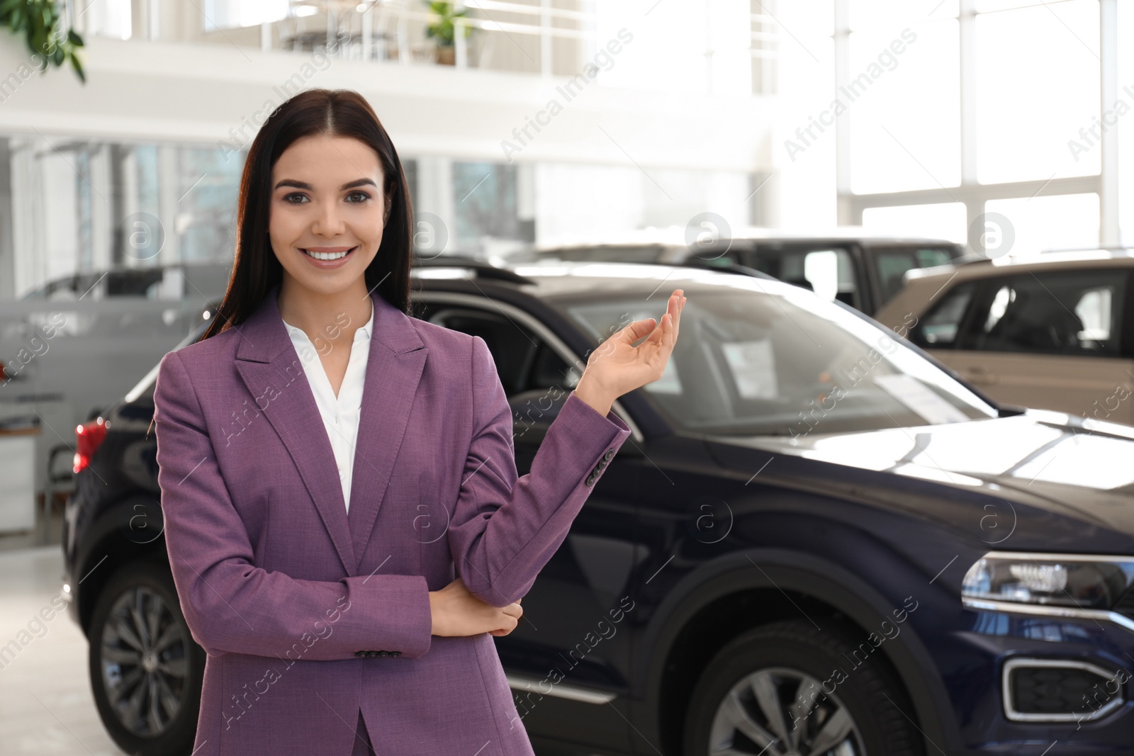 Photo of Happy young saleswoman in modern car salon