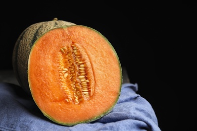 Photo of Tasty ripe cantaloupe melons on napkin against black background