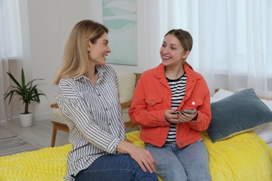 Photo of Happy mother and her teenage daughter spending time together with phone at home