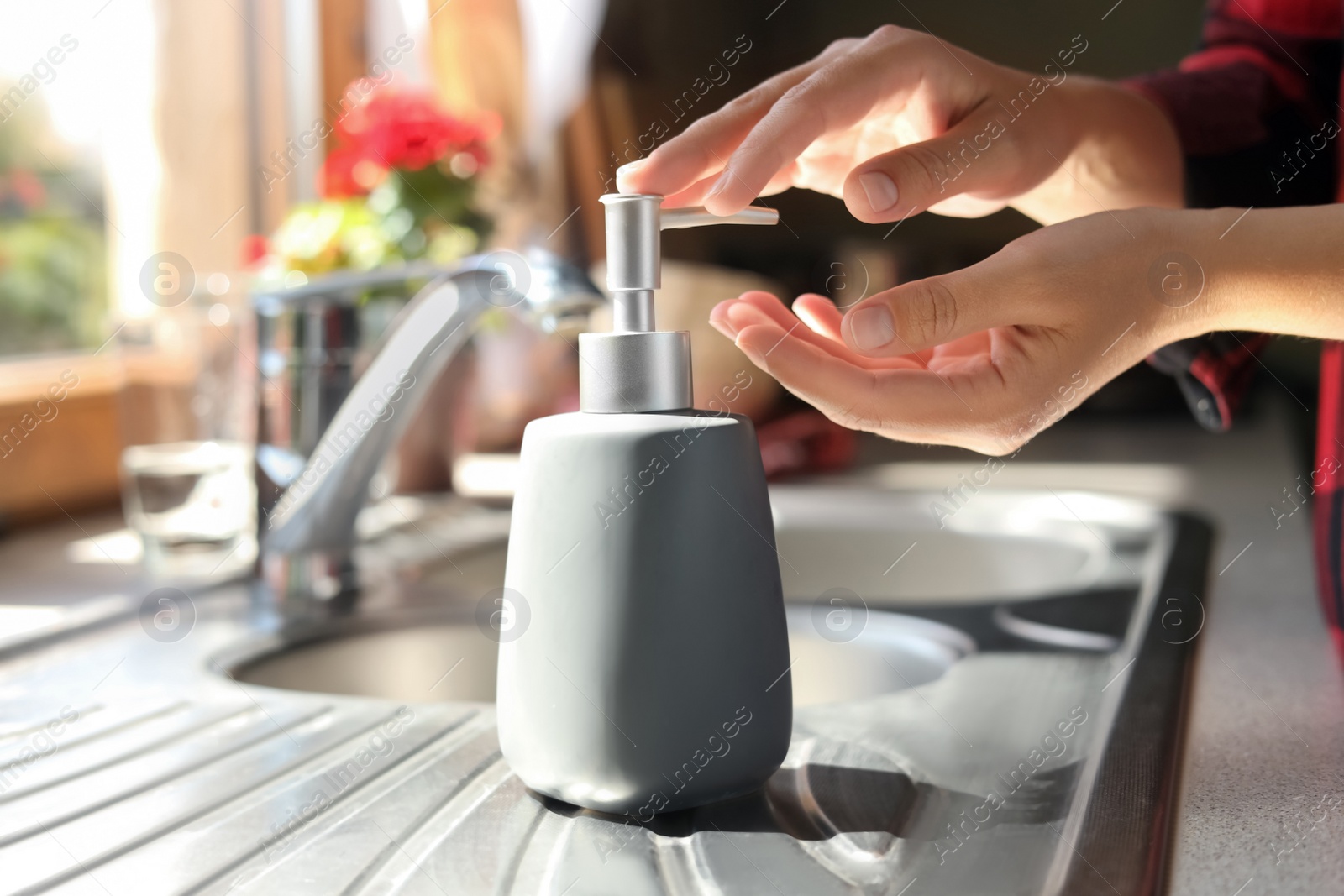 Photo of Woman using liquid soap dispenser in kitchen, closeup