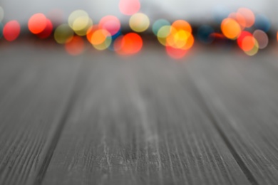 Photo of Colorful lights on wooden table, blurred view. Space for text