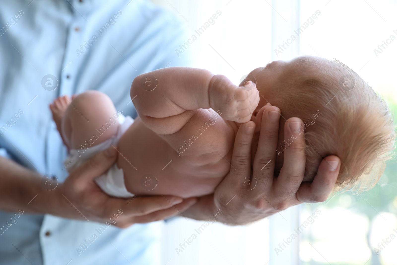 Photo of Father holding his newborn baby at home, closeup