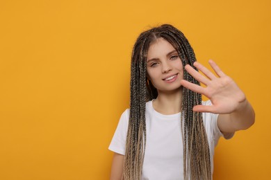 Photo of Young woman giving high five on yellow background, space for text