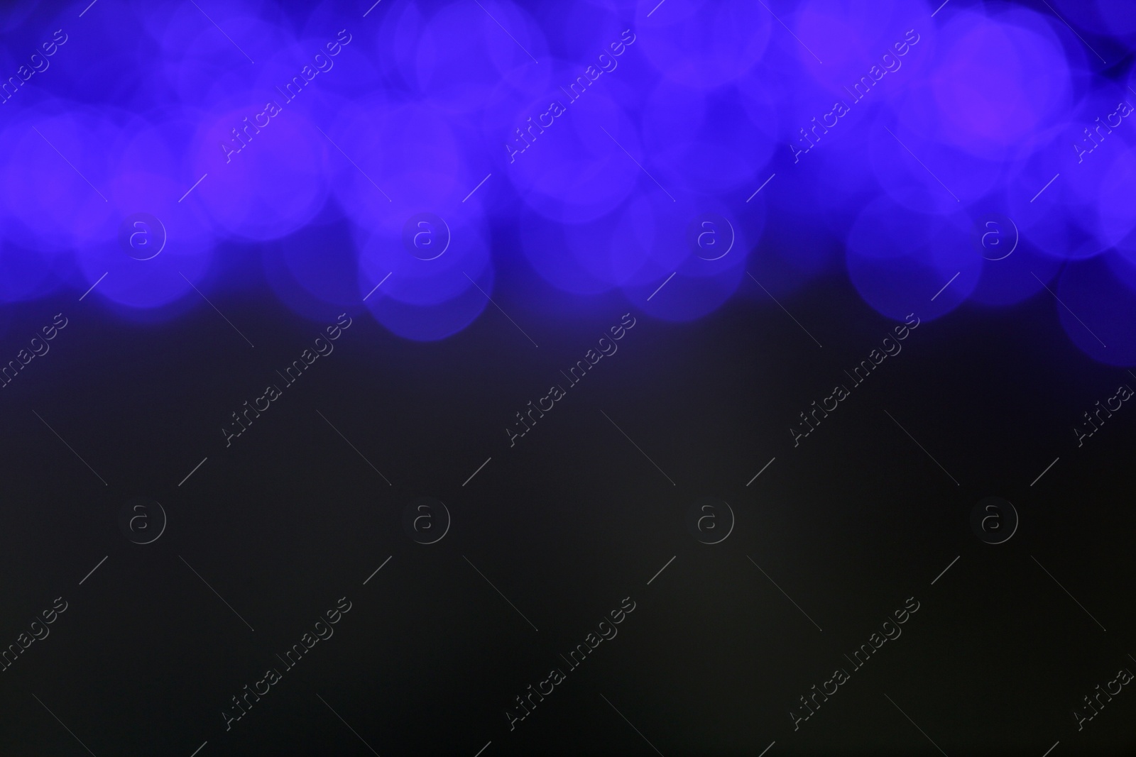 Photo of Blurred view of blue Christmas lights on grey background. Space for text