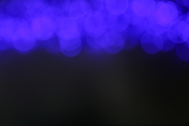 Photo of Blurred view of blue Christmas lights on grey background. Space for text