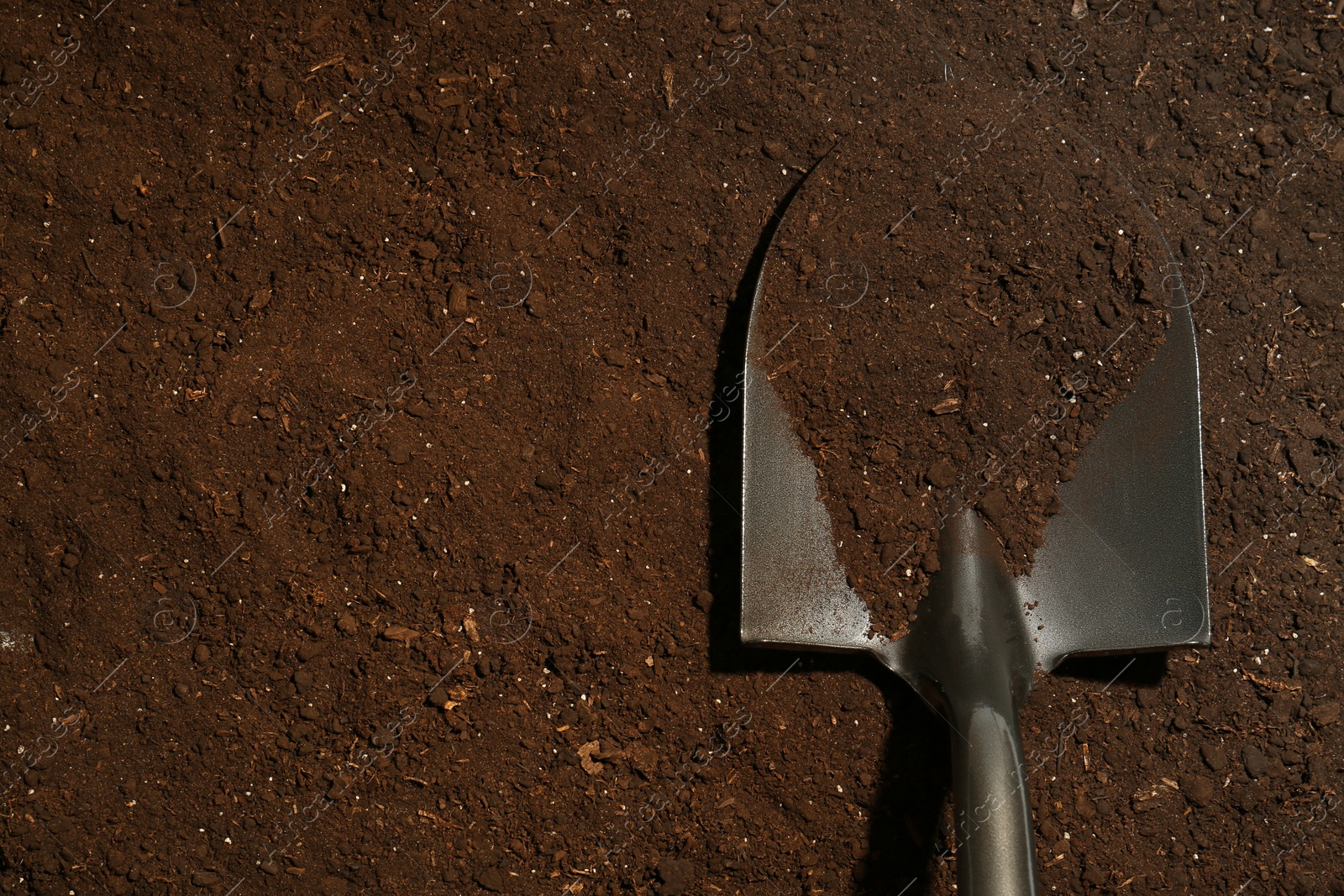 Metal shovel on fertile soil, top view and space for text. Gardening tool Photo of Metal shovel on fertile soil, top view and space for text. Gardening tool
