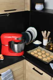 Photo of Modern stand mixer, ingredients, tableware and baked cookies on countertop in kitchen