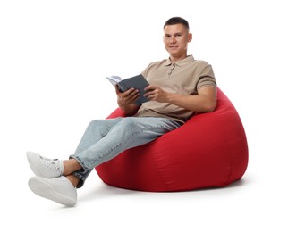 Photo of Handsome man with book sitting on red bean bag chair against white background
