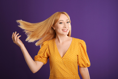 Photo of Beautiful young woman with blonde hair on purple background