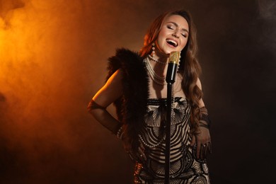 Beautiful young woman with microphone singing in color lights and smoke