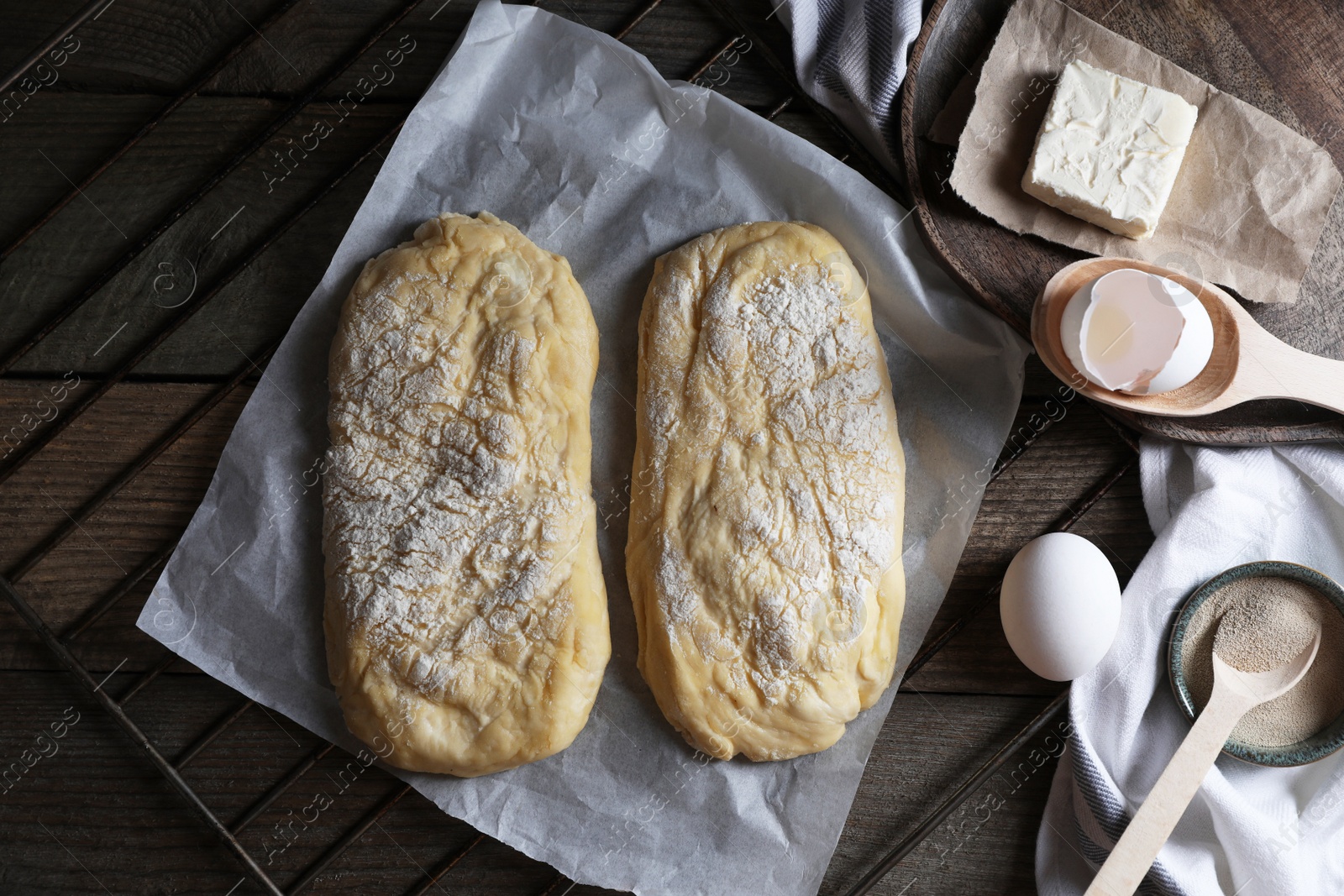 Photo of Raw dough for ciabatta and flour on wooden table, flat lay