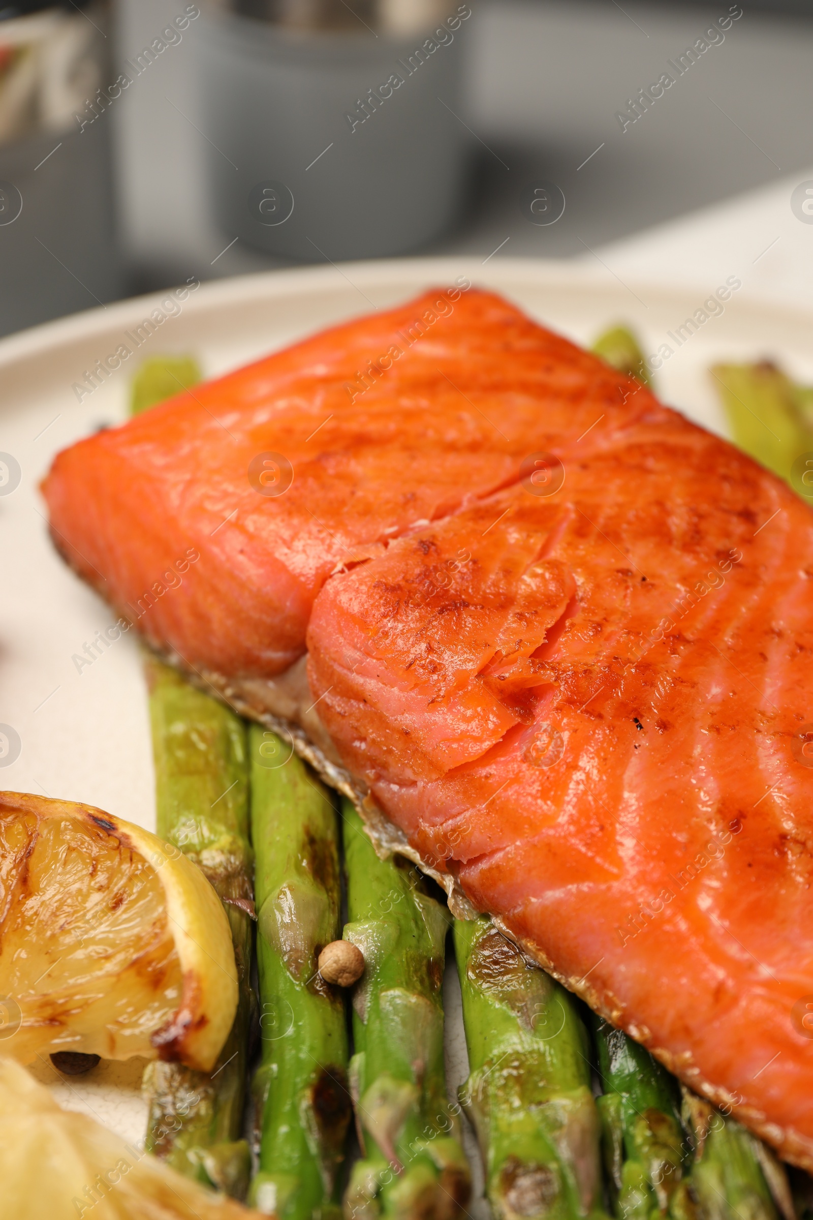 Photo of Tasty grilled salmon with asparagus, tomatoes and lemon on plate, closeup