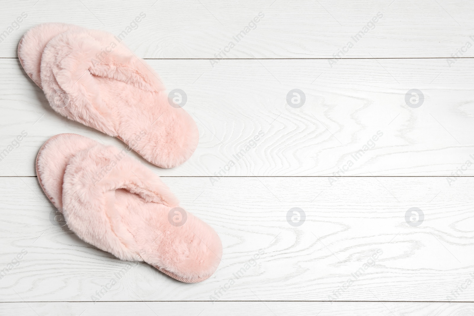 Photo of Pair of soft slippers on white wooden background, flat lay. Space for text