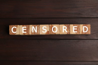 Cubes with word Censored on wooden table, flat lay