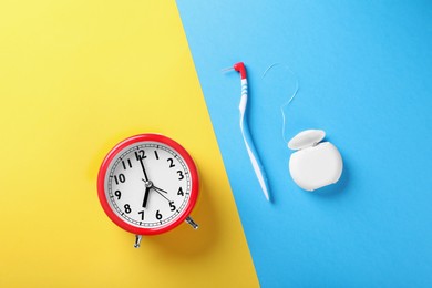 Container with dental floss, toothbrush and alarm clock on color background, flat lay