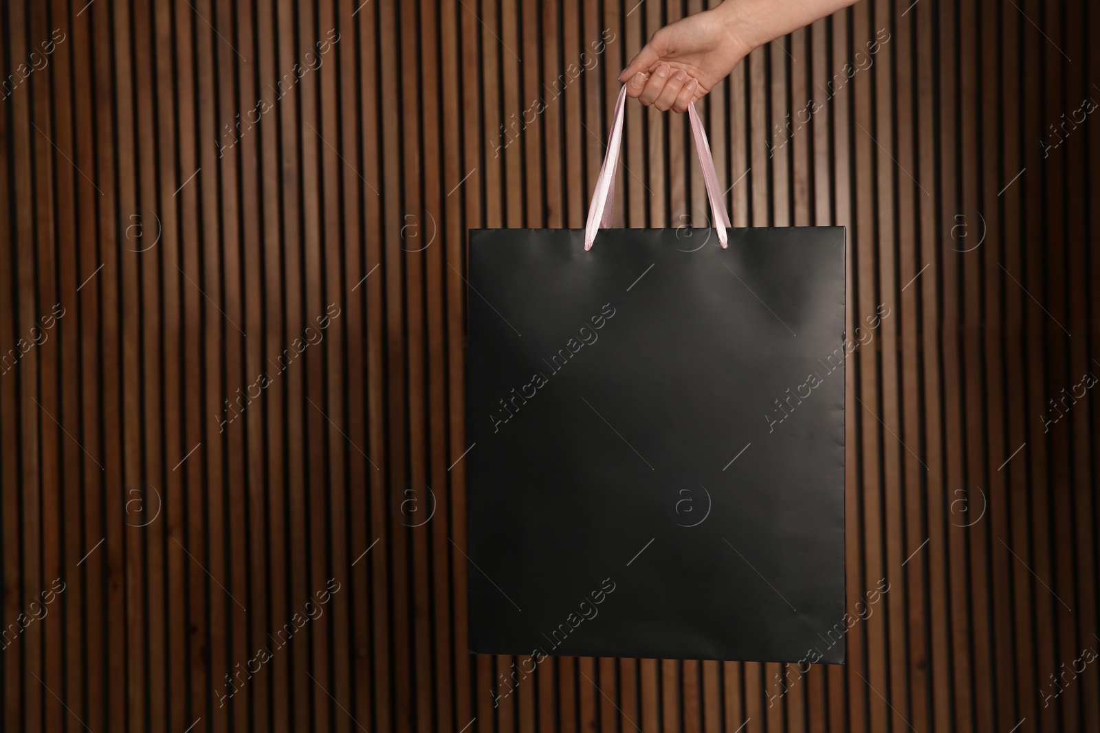 Photo of Woman holding paper shopping bag on wooden background. Mock up for design