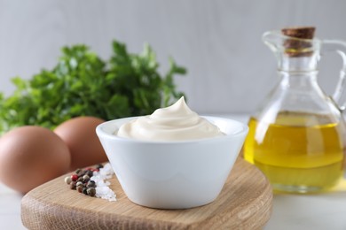 Tasty mayonnaise sauce in bowl, spices and ingredients on table, closeup