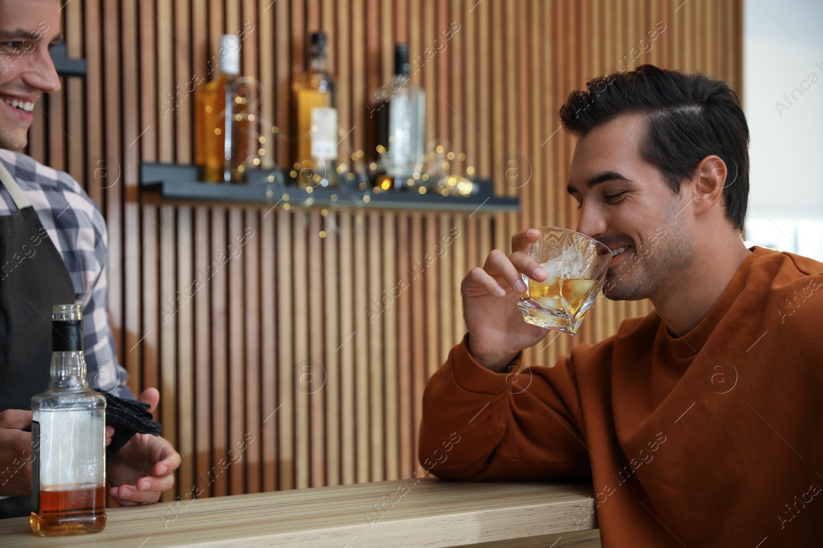 Photo of Young man with glass of whiskey in bar