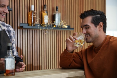 Young man with glass of whiskey in bar