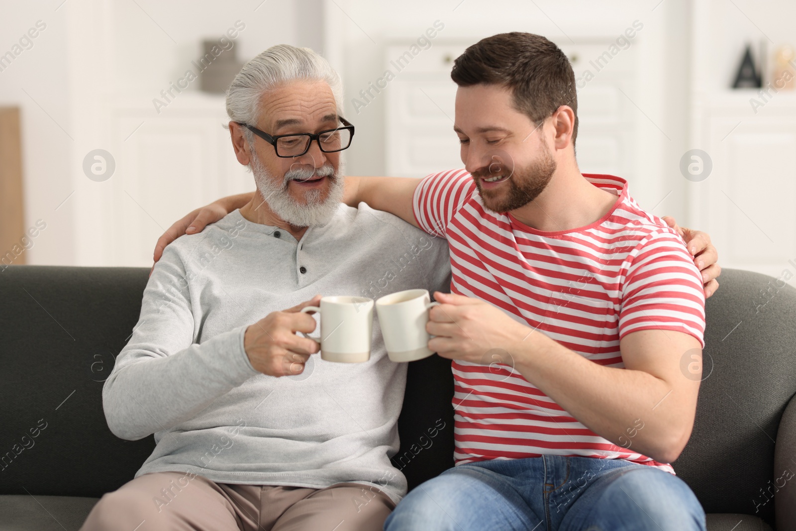 Photo of Happy son and his dad with cups at home