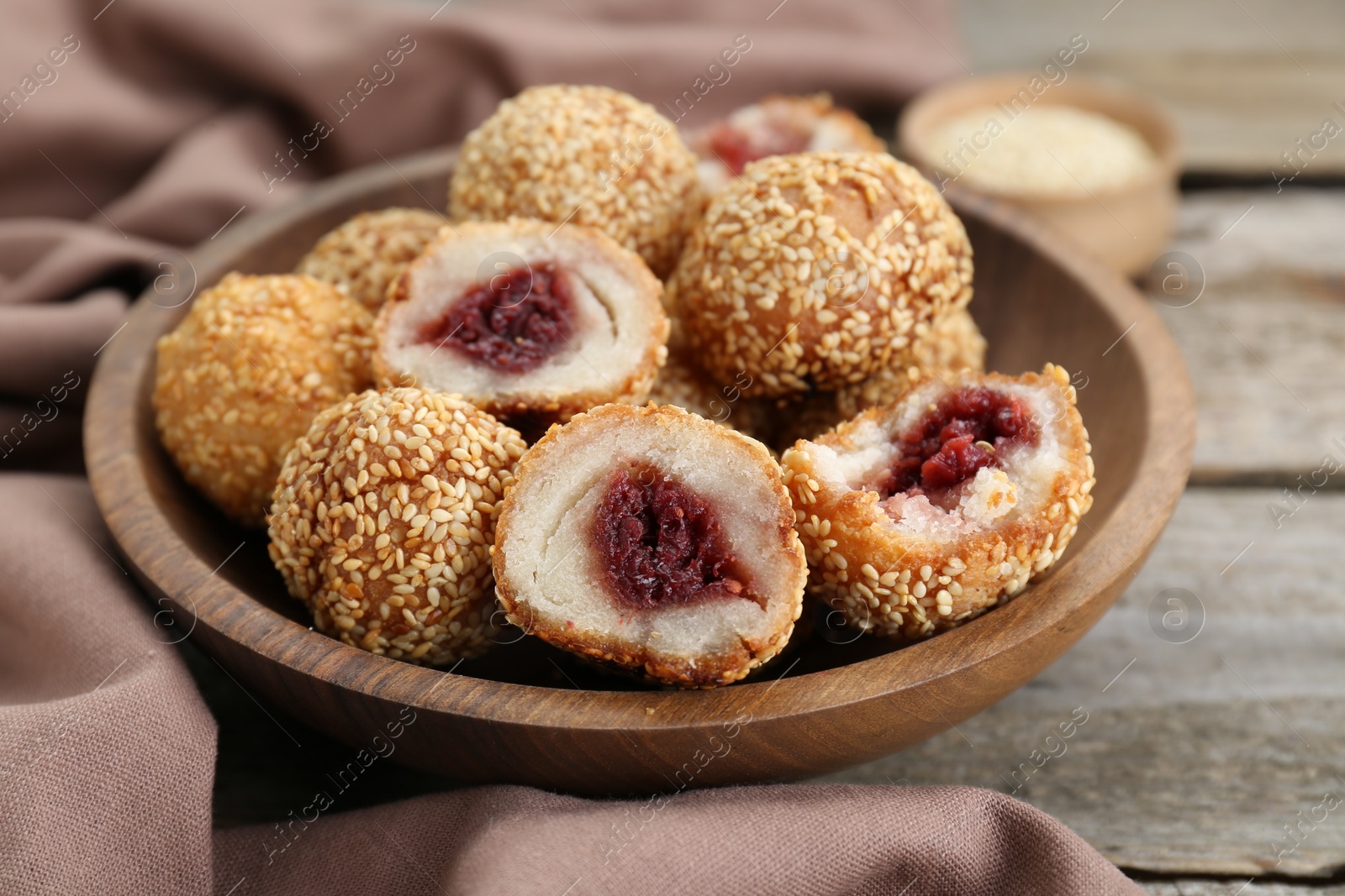 Photo of Delicious sesame balls with red bean paste on wooden table, closeup