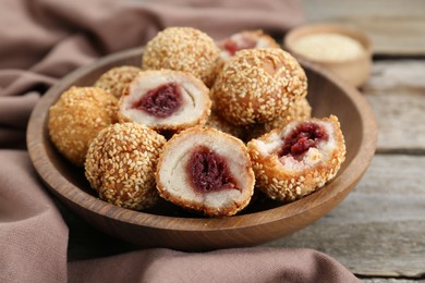 Delicious sesame balls with red bean paste on wooden table, closeup