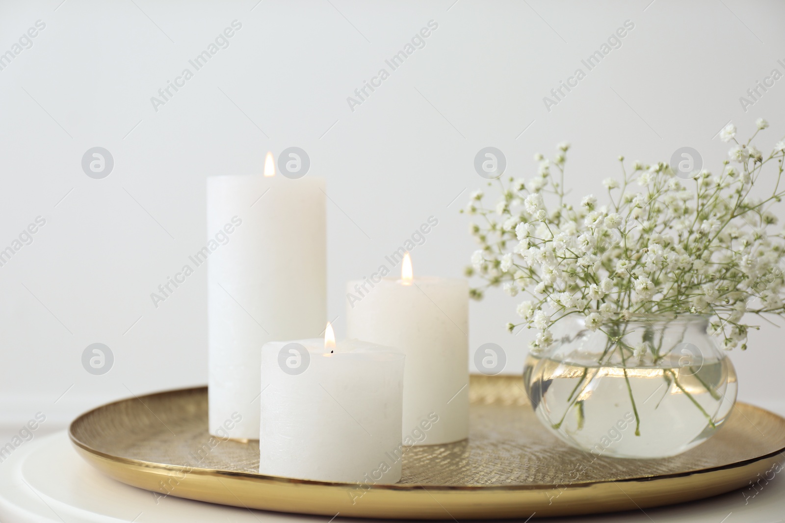 Photo of Vase with beautiful flowers and burning candles on table indoors. Interior elements