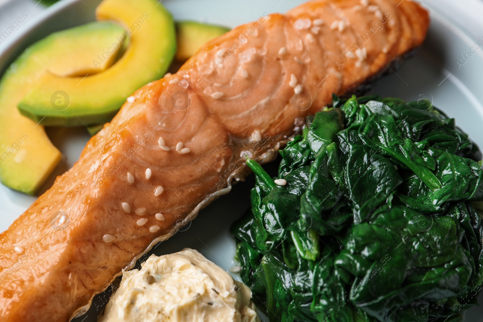 Photo of Tasty salmon with spinach and avocado, closeup