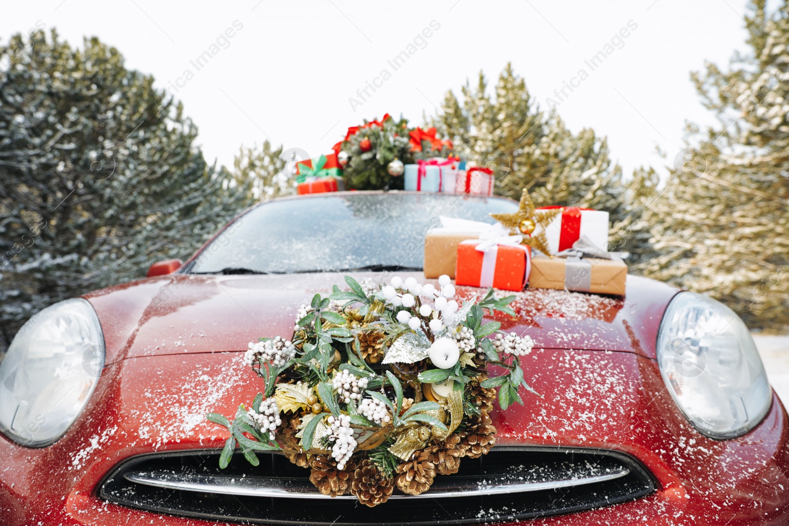 Photo of Car with Christmas wreath, tree and gifts in winter forest, closeup