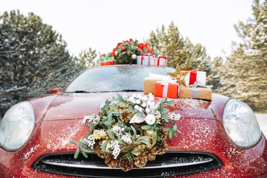 Car with Christmas wreath, tree and gifts in winter forest, closeup