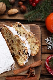 Photo of Traditional Christmas Stollen with icing sugar on wooden table, flat lay