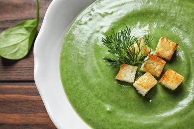 Photo of Fresh vegetable detox soup made of spinach with croutons in dish on table, closeup