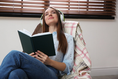 Woman listening to audiobook in chair at home