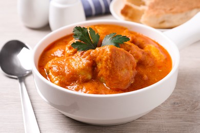 Photo of Bowl of delicious chicken curry on white wooden table