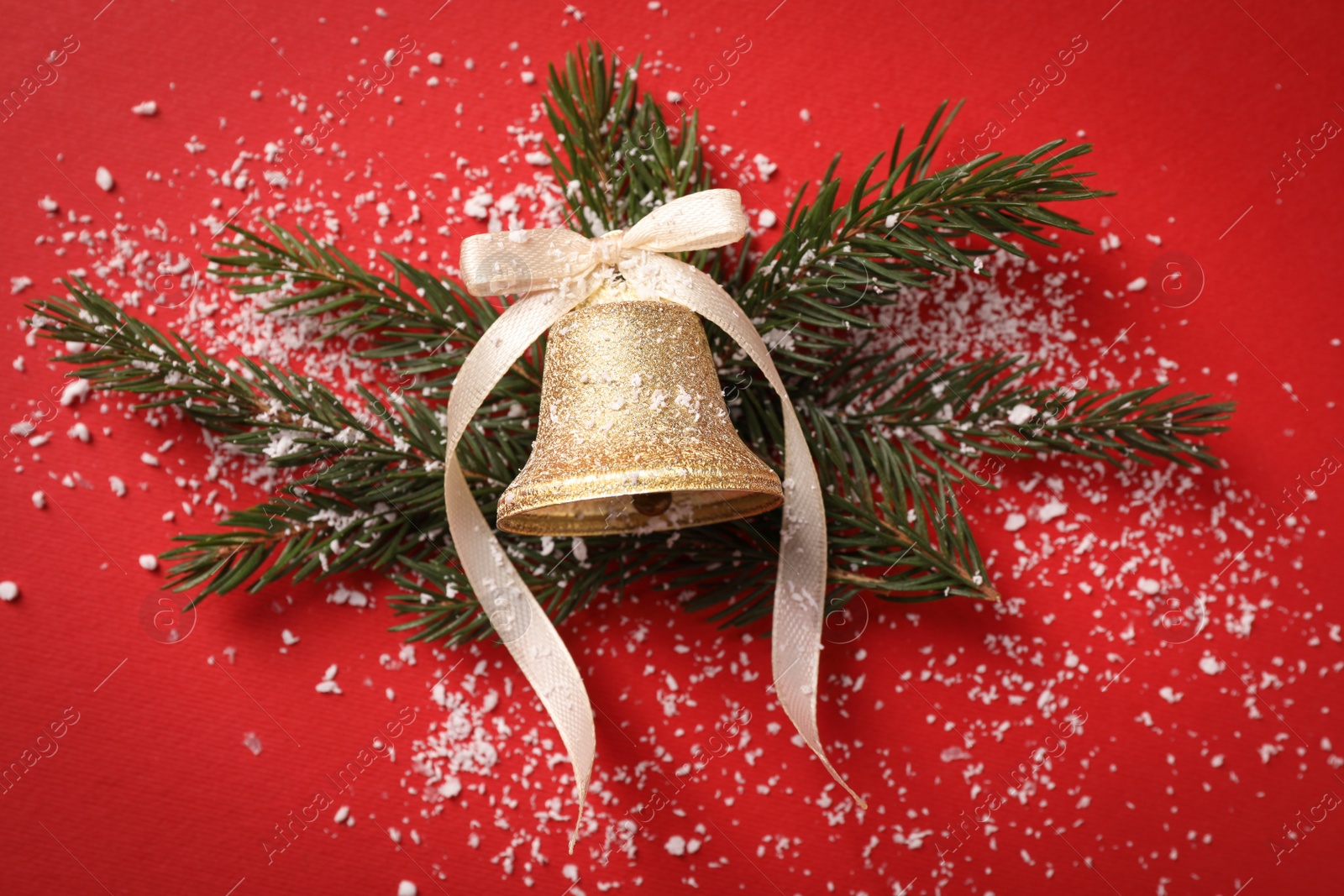 Photo of Bell, fir branches and artificial snow on red background, flat lay. Christmas decor