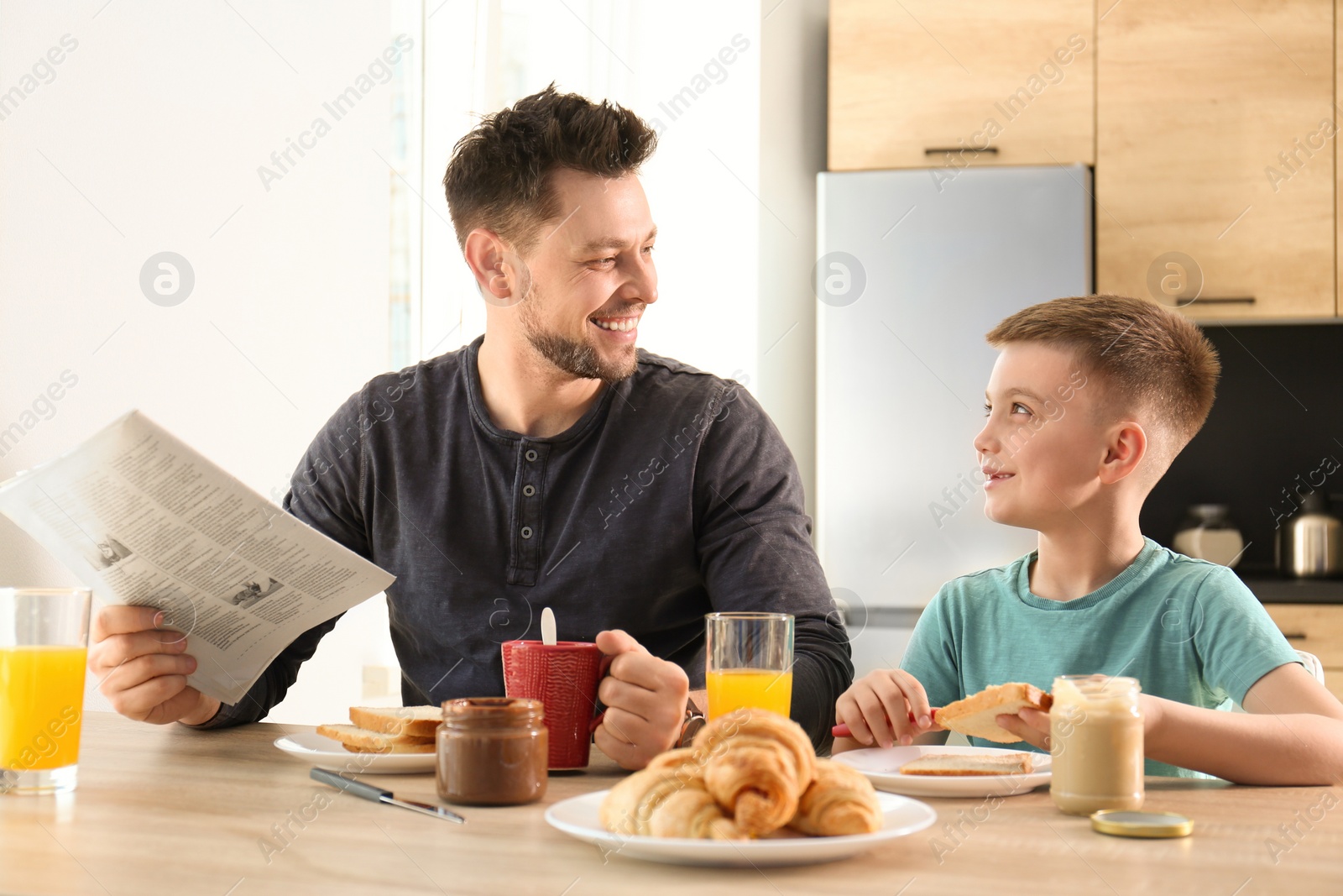 Photo of Dad and son having breakfast together in kitchen