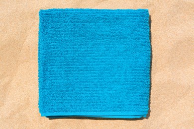 Photo of Soft blue beach towel on sand, top view