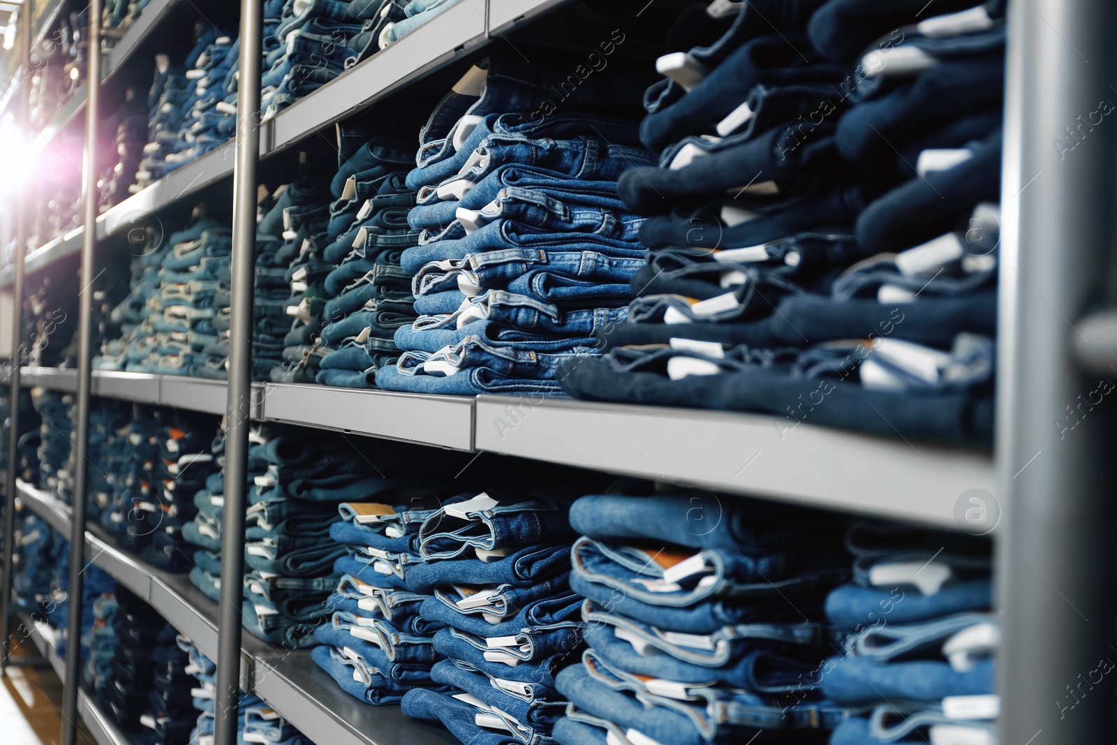 Photo of Collection of stylish jeans on shelves in shop